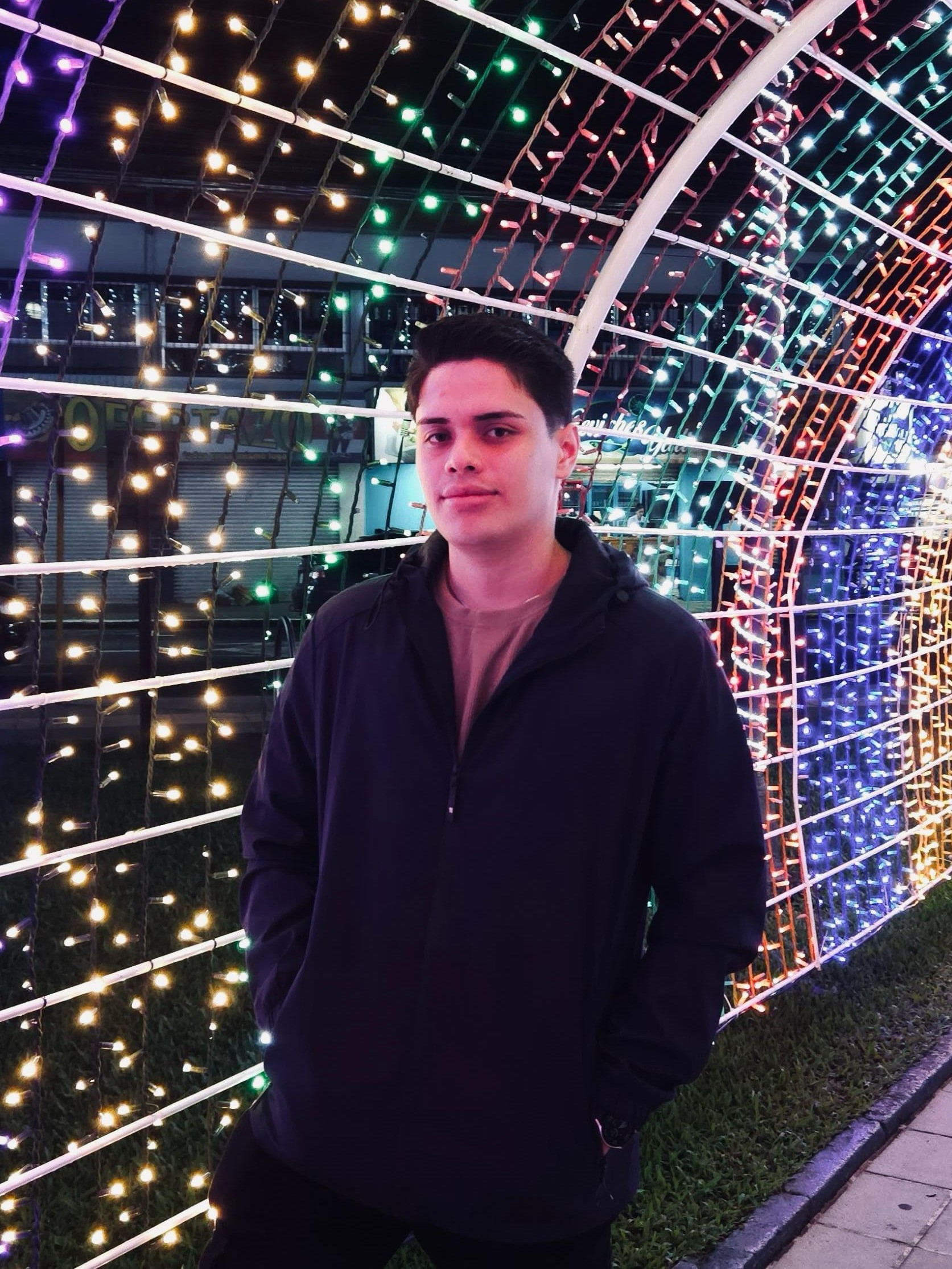 Brandon Zárate  smiling in a red plaid shirt and tortoise shell glasses